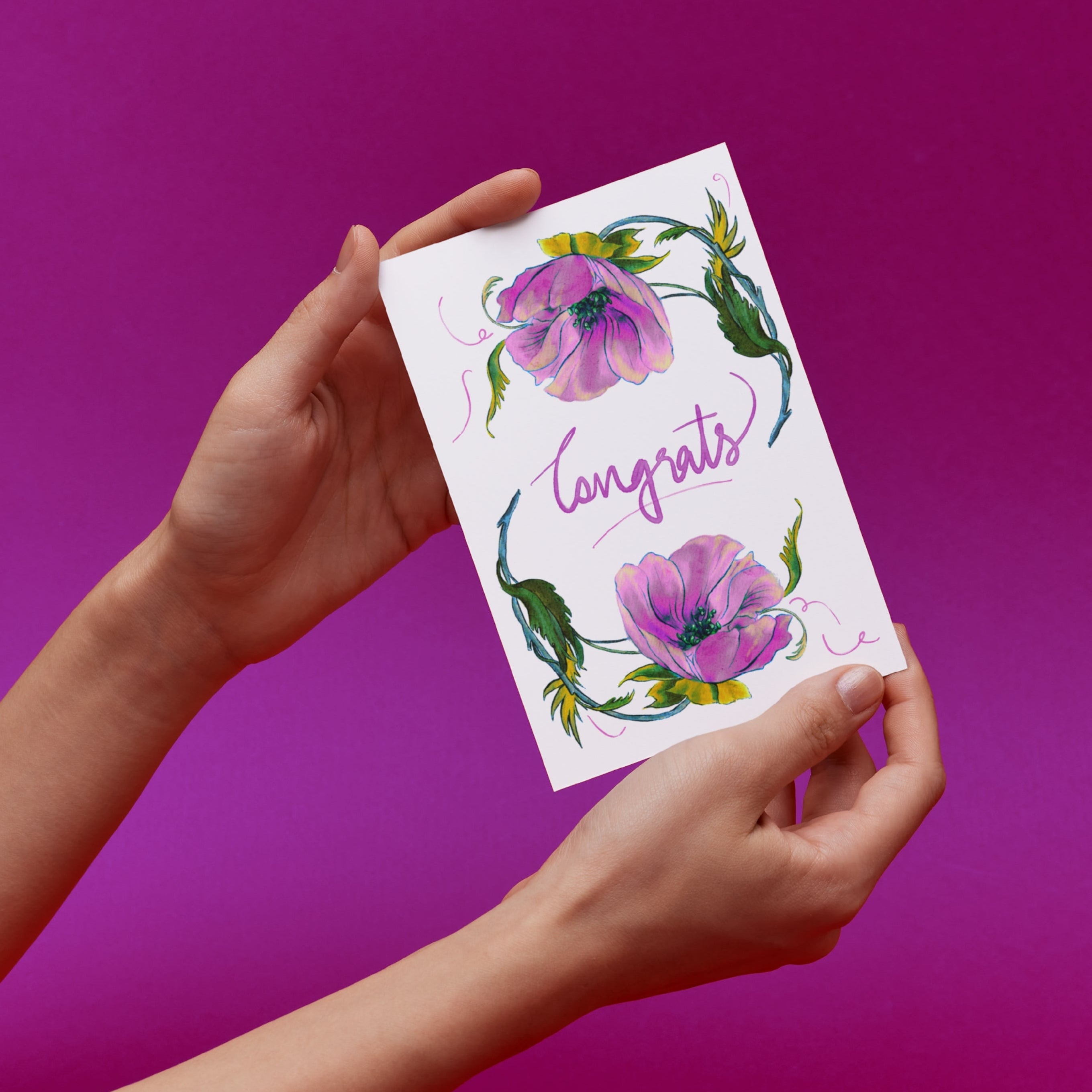 Hands holding a card with original illustrated floral design and 'Congrats' text 