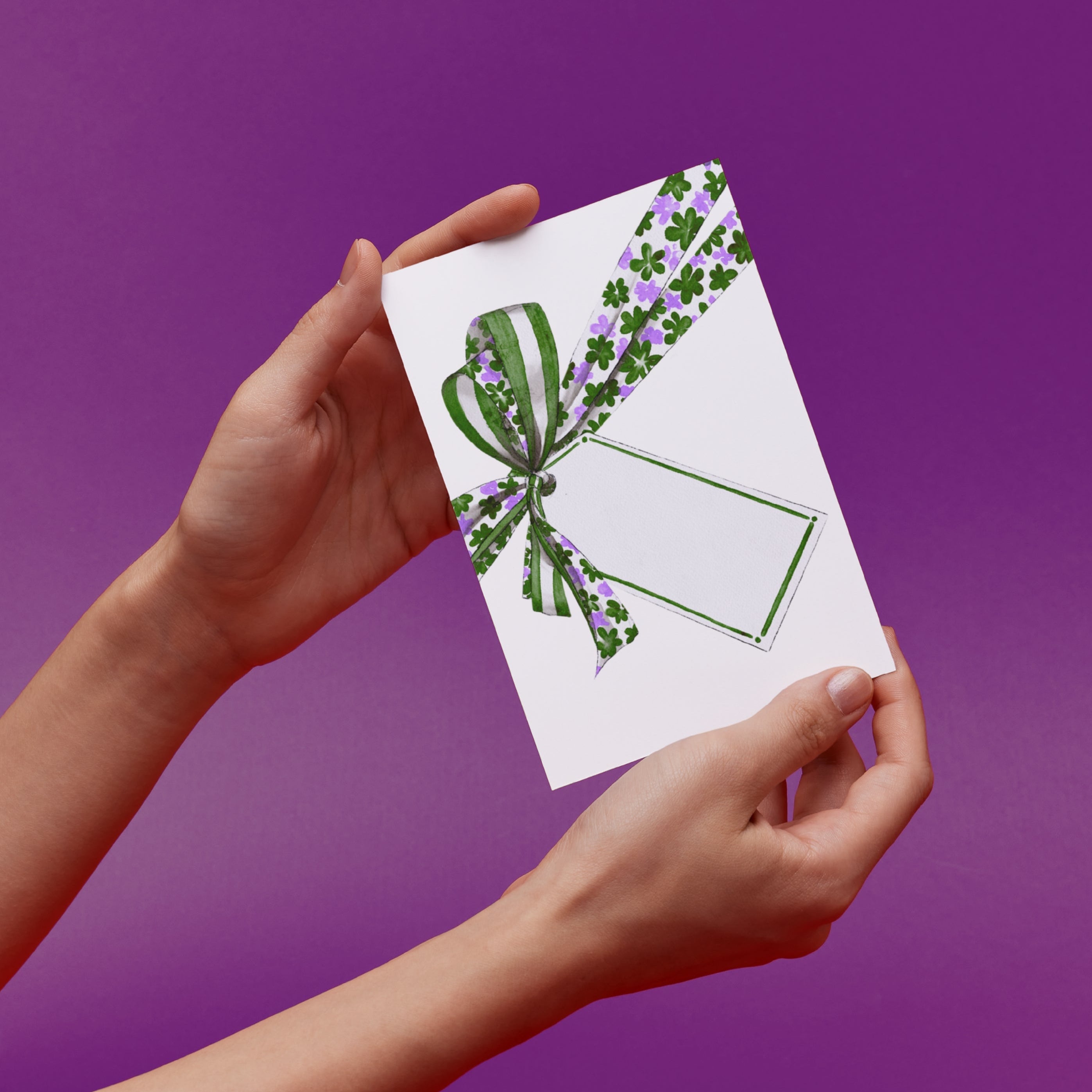 Hands holding a card with a green and lavender ribbon and blank gift tag original illustration 