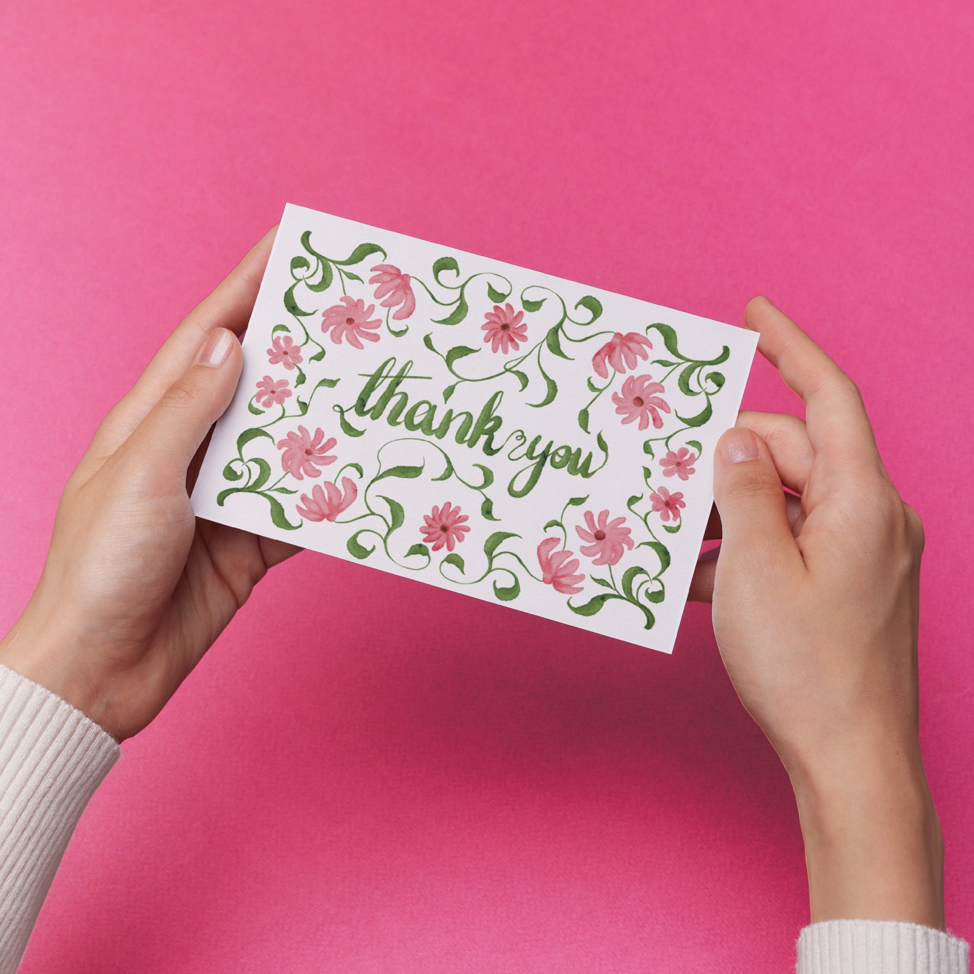 Hands holding a 'thank you' card with original delicate pink floral design